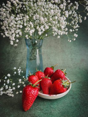 Kırsal ahşap arka planda beyaz kasede taze kırmızı çilekler.