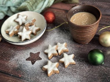 Tabaktaki Noel kurabiyeleri ve ahşap masadaki dekoratif süsler.