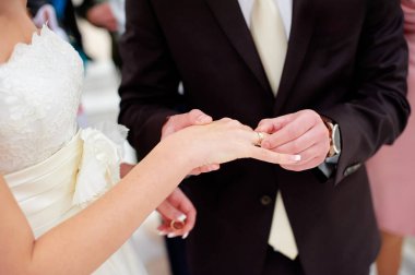 Aşk ve evlilik. Düğün töreni. Damat, gelinin parmağına altın yüzüğü takıyor..