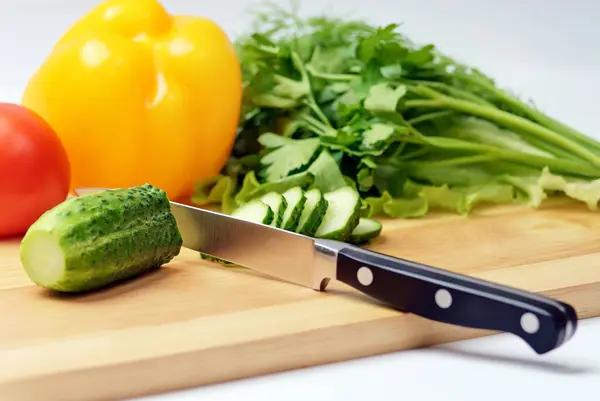 Chopping board with tomato, cucumber, parsley, sweet pepper and knife