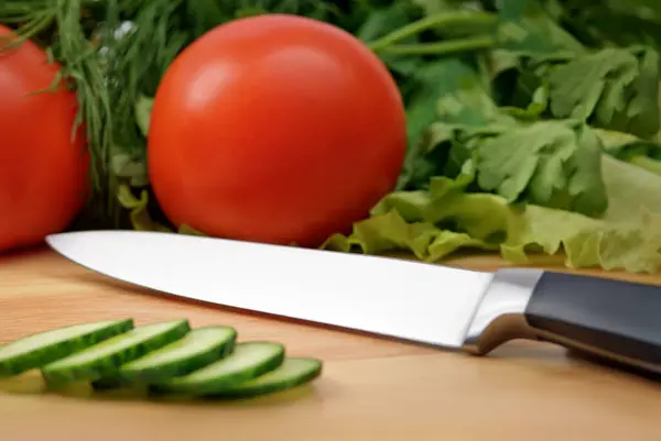 Chopping board with tomato, cucumber, parsley and knife