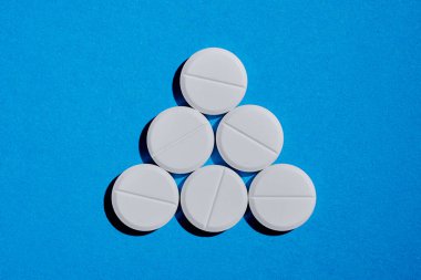 Eczane sağlık hizmeti konsepti. Mavi arkaplanda beyaz tableti üçgen şeklinde kapat.