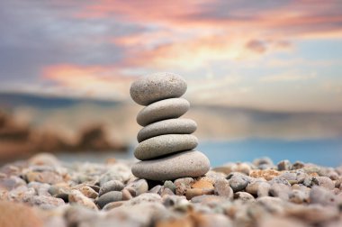 Arka planda deniz batımı olan çakıl taşı yığınları.