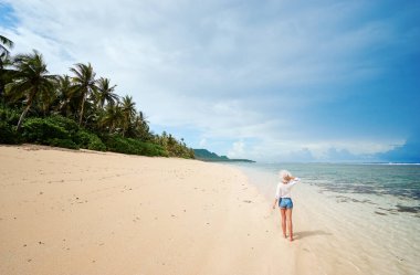 Deniz kıyısında bir tatil. Genç bir kadının tropikal beyaz kumsalda yürüyüp gidişinin arkası..