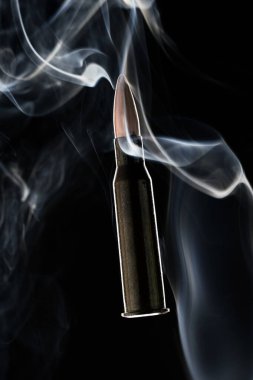 Siyah arkaplanda dumandaki tüfek mermisi.