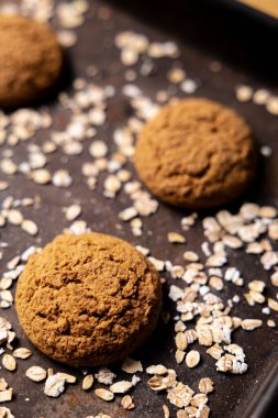 El yapımı ve sade dört yulaflı kurabiye. Koyu gıda estetiği, siyah arka plan ve birkaç yulaf ezmesi..