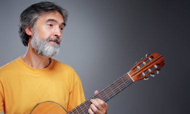 Akustik gitarı olan yaşlı sakallı bir adam.