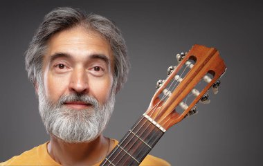 Akustik gitarı olan yaşlı sakallı bir adam.