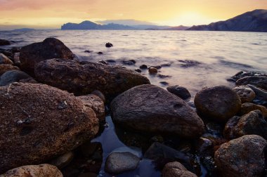 Şafak vakti deniz kıyısında büyük kayalar ve taşlar.