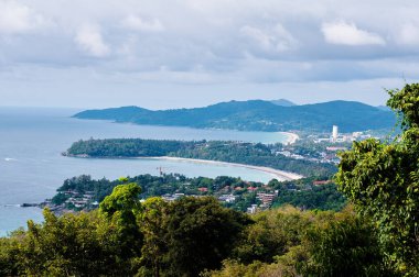 Kata ve Karon plaj manzaralı. Okyanus kıyıları, yeşil tepeler, bulutlu gökyüzü olan güzel bir manzara. Phuket, Tayland.