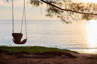 Rahatlama zamanı. Güzel gün batımı manzaralı deniz kıyısında sallan..