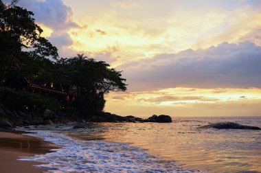Okyanus sahilinde güzel bir gün batımı. Gökyüzü suya yansıyor.