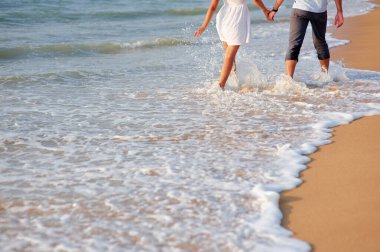 Denizde balayı. Kumlu plajda yürüyen sevgi dolu çiftin arka görünümü