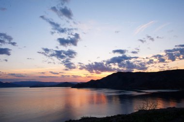 Deniz kıyısında gün batımının olduğu güzel bir manzara..