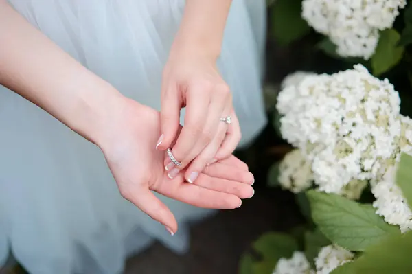 婚戒的概念 美丽的新娘手拿着华丽的戒指在白花旁玩耍 — 图库照片