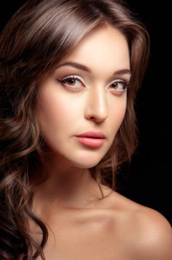 Kendine güvenen bir güzellik. Siyah arka planda dikilirken kameraya bakan genç ve güzel bir kadının portresi.