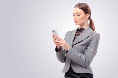 Arkadaşıma mesaj yazıyorum. Kendine güveni tam genç bir kadın cep telefonu tutuyor ve beyaz arka planda dururken ona bakıyor.