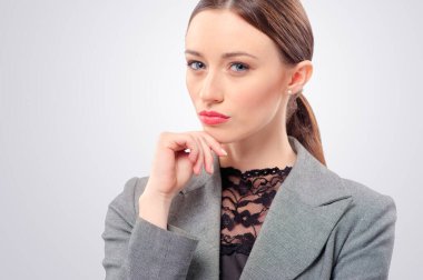 Düşünceli genç bir iş kadını yüzüne dokunuyor, gri renkte soyutlanmış.