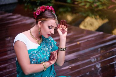 Gelinlik makyajı ve takılarıyla geleneksel giysiler içinde güzel bir Hintli kadın. Muhteşem gelin geleneksel olarak Hindistan 'da açık havada giyinir. Sari 'de kız Bollywood dansçısı ve ellerinde kınayla