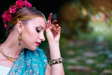 Gelinlik makyajı ve takılarıyla geleneksel giysiler içinde güzel bir Hintli kadın. Muhteşem gelin geleneksel olarak Hindistan 'da açık havada giyinir. Sari 'de kız Bollywood dansçısı ve ellerinde kınayla