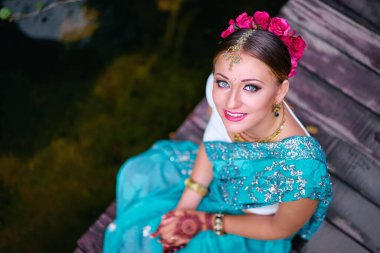 Gelinlik makyajı ve takılarıyla geleneksel giysiler içinde güzel bir Hintli kadın. Muhteşem gelin geleneksel olarak Hindistan 'da açık havada giyinir. Sari 'de kız Bollywood dansçısı ve ellerinde kınayla
