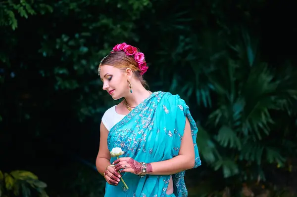 ブライダルメイクとジュエリーの伝統的なインドの服の美しい若い白人女性 サリとヘンナのボリウッドダンサーが緑の庭を歩いている — ストック写真