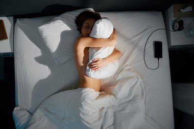 Genç kadın yatakta üstten görünüm yastık sarılma.