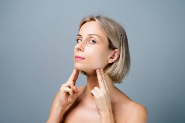 Cilt bakımı. Güzel yüz masajlı sarışın kadın. Makyaj yok. Gri arkaplan.