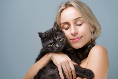 Genç şişkin kadının stüdyo portresi ve onun sevimli siyah tekir kedisi.