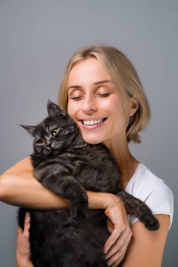 Genç şişkin kadının stüdyo portresi ve onun sevimli siyah tekir kedisi.