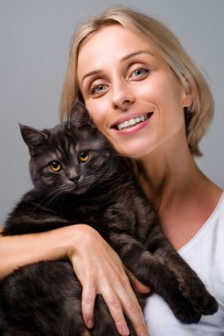 Genç şişkin kadının stüdyo portresi ve onun sevimli siyah tekir kedisi.