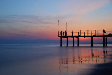 Deniz sahilinde güzel bir gün batımı. Gökyüzü suya yansıyor.