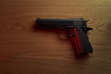 Ahşap masada büyük siyah bir tabanca..