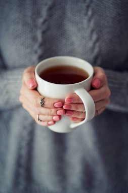 Rahat bir ev. Bir fincan sıcak kahve ya da çay tutan kadın elleri.