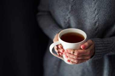 Rahat bir ev. Bir fincan sıcak kahve ya da çay tutan kadın elleri.