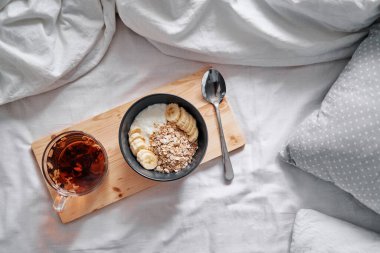 İyi sabahlar. Yatakta kahvaltı. Bir kase granola ve bir fincan sıcak çay..
