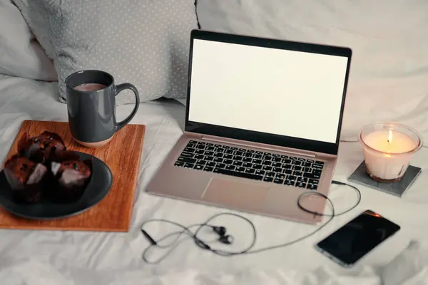 Breakfast in bed: a wooden tray with granola and cup of cocoa with a laptop on background.