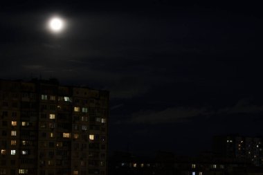 Büyük dolunay gece gökyüzünde şehrin üstünde.