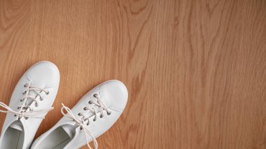 Ahşap arka planda bir çift beyaz ayakkabı..