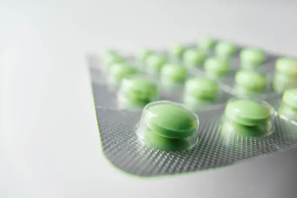 Green pills. Blister with pills on white background.