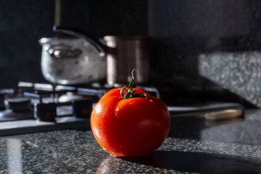 Fresh tomato on kitchen table, ready for cooking. Copyspace for text. Concept of food preparation, kitchen on background.