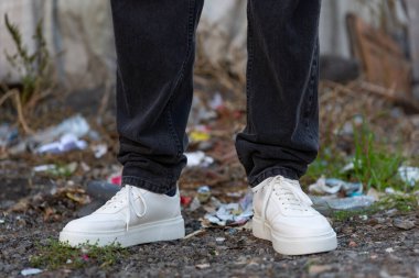 A man's legs in close-up on a dirty street. The concept of garbage on the streets of the city.