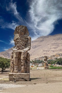 The Colossi of Memnon, two massive quartzite stone statues dedicated of the Pharaoh Amenhotep III. Completion date 1350 BCE, height 18 m (60 ft), weigh 720 tons each. Location West of Luxor, Egypt.