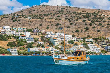SpINALONGA, GREECE - 24 Temmuz 2021: Girit mimarisinde, Mirabello Körfezi kıyısında, Elounda Limanı ile Spinalonga adası arasında, turist, otel ve turizm merkezli küçük yat. 