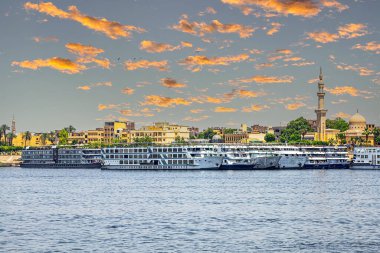 LUXOR, EGYPT - APRIL 24, 2022: Tourist cruise ships on the Nile river, anchored in the tourist port. Sunset light.