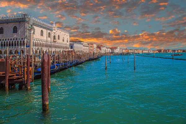 stock image VENICE, ITALY - MARCH 16, 2023: View along the Riva degli Schiavoni, with the Doges' Palace, traditional Venetian architecture, boats, gondolas and the sea. Sunset light.