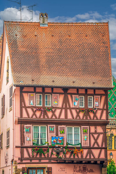 COLMAR, FRANCE - MAY 5, 2023: Traditional Alsatian house, with cheerful decorations on the facade, located in a medieval building with typical architecture of the area in old town.