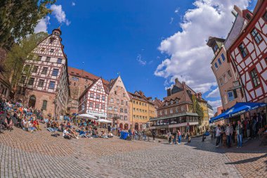 NUREMBERG, ALMANY - 30 Nisan 2023: Ortaçağ Tiergartnertor Meydanı 'nda dinlenen turistler, Albrecht Drer Evi ve Pilatus Evi de dahil olmak üzere yarı keresteli evlerle çevrili eski kasaba.