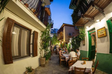 Skiatos Kasabası, Skiatos Adası, GREECE - 22 AĞUSTOS 2023: Eski şehrin Yunan Akdeniz mimarisinde geleneksel tavernalarla dolu dar sokakların akşam manzarası.