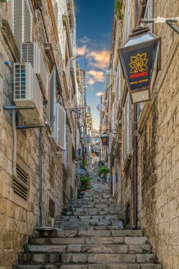 DUBROVNIK, CROATIA - 18 Ağustos 2022: Şehrin tarihi merkezinde yer alan küçük restoranları, otelleri, turistik mekanları ve resimli hediyelik eşya dükkanları olan dar sokaklar.